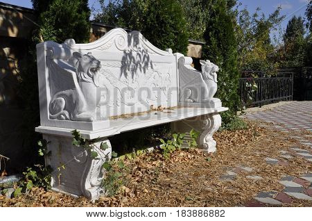 carved white bench with lions in the Park under a tree