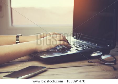 woman hand computer and glasses and phne on wooden table