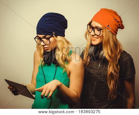 two hipster girls friends use digital tablet, studio shot over gray vackground