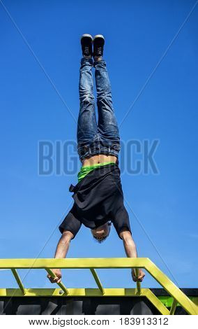 Young Athlete doing a Hand Stand On Parallel Bars In An Outdoor Gym - Street Workout Exercises.