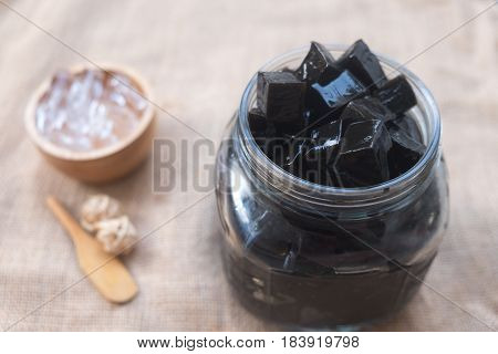 Grass jelly dessert in glass jar with ice (focus grass jelly)