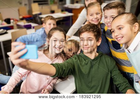 education, elementary school, children and people concept - group of kids taking selfie with smartphone in corridor