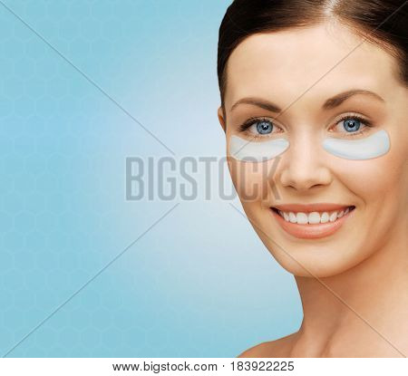 beauty, cosmetology, hydration, people and rejuvenation concept - close up of beautiful young woman face with hydrogel under-eye patches over blue background