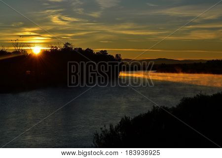 Beautiful sunrise and its rays at the river. Sunshine beams in misty foggy river at early morning.