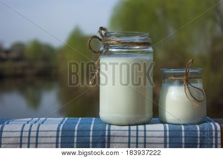 wo jars of fermented milk product against the background of the river