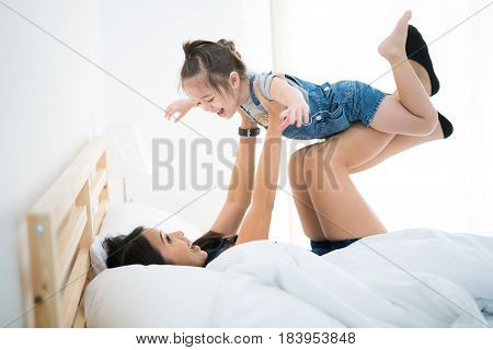 Mother and her daugther play togather on the bed in bedroom family mon and kid concept