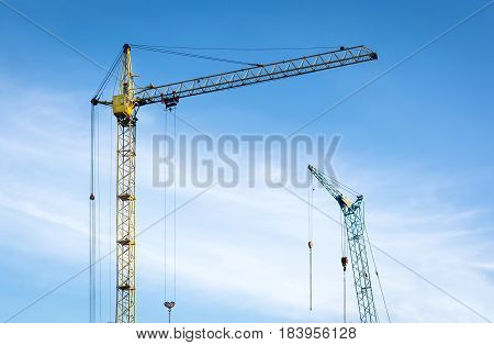 Tower cranes on a blue sky background. The construction of houses.