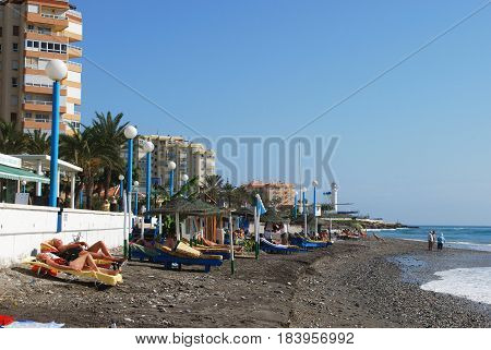 TORROX COSTA, SPAIN - OCTOBER 27, 2008 - Tourists relaxing on the beach with apartment blocks to the rear Torrox Costa Malaga Province Andalusia Spain Western Europe, October 27, 2008.