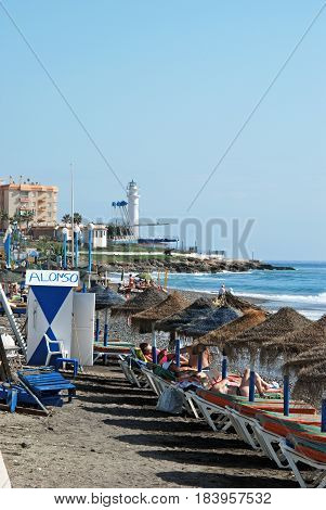 TORROX COSTA, SPAIN - OCTOBER 27, 2008 - Tourists relaxing on the beach with the lighthouse to the rear Torrox Costa Malaga Province Andalusia Spain Western Europe, October 27, 2008.