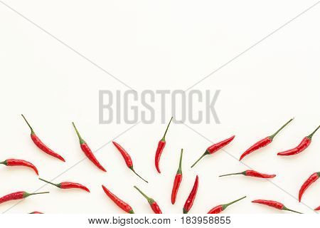 red hot chili peppers, popular spices concept - beautiful handful of red hot pepper pods scattered on white background, top view, flat lay, empty space for the text