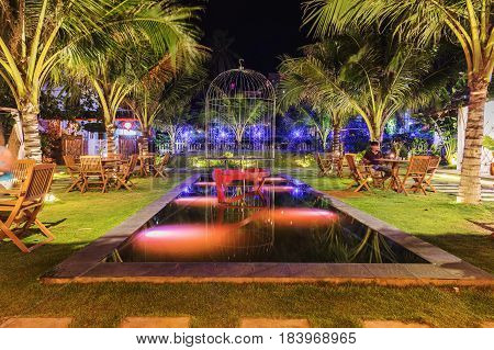MUINE VIETNAM - MARCH 25 2017. Romantic garden with candles camp. Garden sitting near the water with tables.
