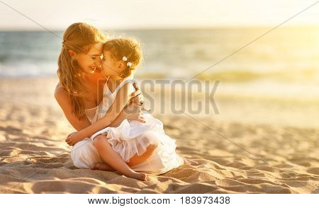 happy family at the beach. mother hugging baby daughter at sunset