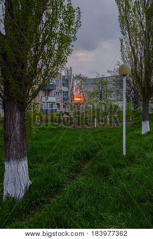 Three-storey house in the village of Uspenskoye, Krasnodar Krai, in the gaps between them see the sunrise, and the grass, trees, flowers.The General background is dark because it's still early.