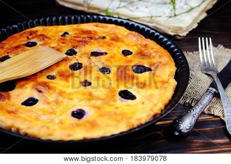 baked cottage cheese pudding with blueberries in a cast iron form with a recipe book