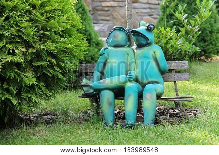 Schodnica Ukraine - June 30 2014: Decorative funny frogs sitting on bench in city park