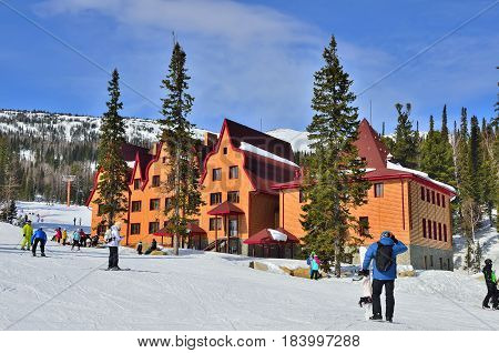 Ski resort Sheregesh Green mountain Mountain Shoria Kemerovo region Russia - March 192017: Beautiful sunny mountain landscape with skiers and snowboarders near the hotel.