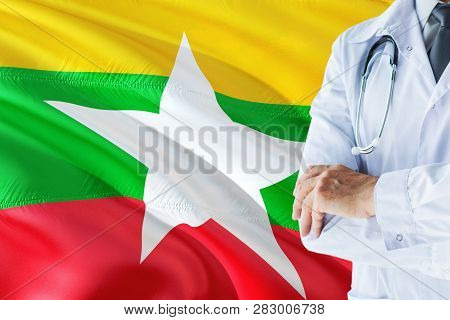 Burmese Doctor Standing With Stethoscope On Myanmar Flag Background. National Healthcare System Conc