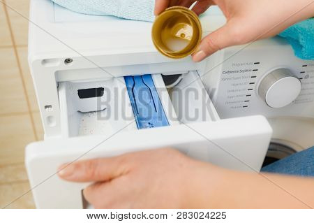 Liquid Powder Detergent And Measuring Cup Pouring Into Machine. Household Duties, Clothes Laundry Ob