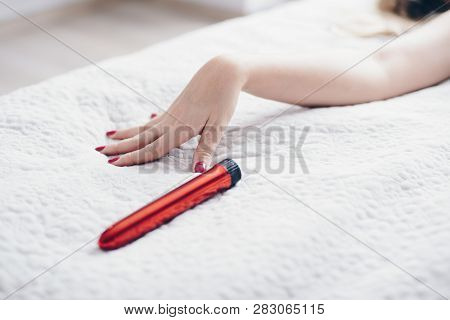 Young Woman’s Hand Reaching For Sex Toy Dildo