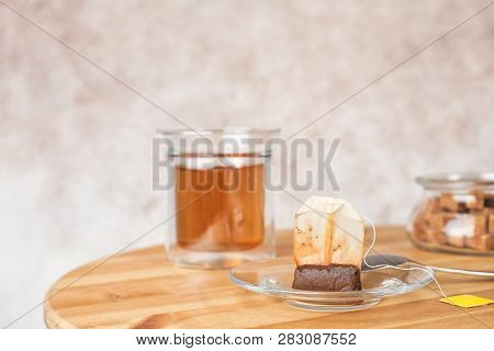 Saucer, Spoon With Used Teabag And Cup On Table. Space For Text