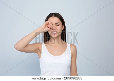 Young Woman Rubbing Eye On Light Background. Annoying Itch