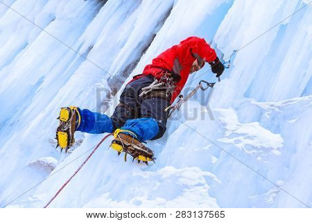 Ice Climber Preraring Running Belay, Screwing Ice Screw Into Glacier Surface