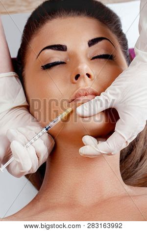 Close Up Of Hands Of Cosmetologist Making Botox Injection In Female Lips And Holding Syringe. Beauti