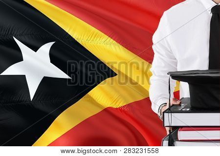 Successful Timorese Student Education Concept. Holding Books And Graduation Cap Over East Timor Flag