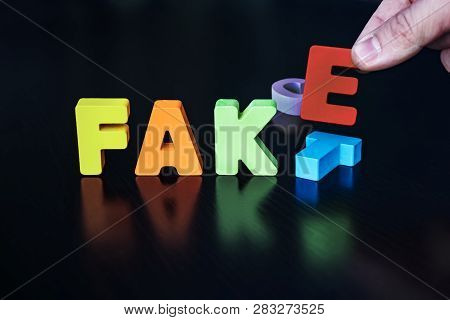 Many-colored Letters Forming Word Fake Instead Of Fact On Black Background. Person Sets Letters F, A