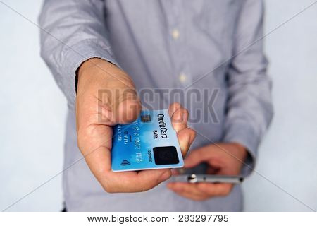 Cropped Short Of Young Man Reaching Out Hand With Blue Credit Card With Fingerprint Sensor And Holdi