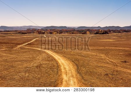Dirt Road Going To The City Of Ouarzazate In Morocco. Ouarzazate With Typical Moroccan Architecture 