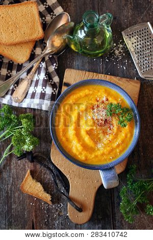 Vegetable Carrot Soup With Parsley, Olive Oil, Grated Cheese And Toasted Bread. Top View