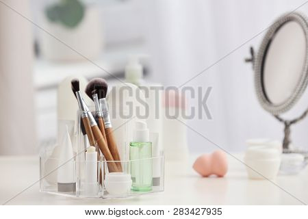 Organizer With Cosmetic Products And Makeup Accessories On Table Against Blurred Background. Space F