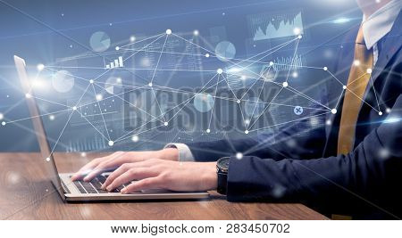 Businessman typing on laptop with linked reports charts grapghs around