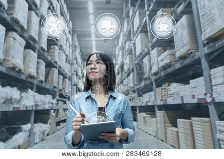 Portrait Of Young Attractive Asian Entrepreneur Woman Looking At Inventory In Warehouse With Smart T