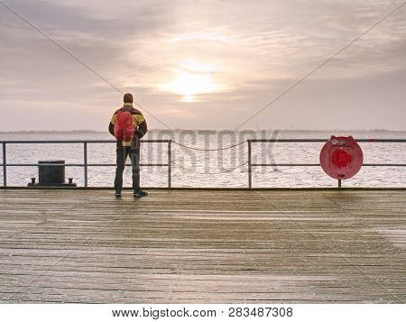 Man Tourist In Autumn Mist On Wooden Pier Above Sea. Depression Dark Atmosphere.