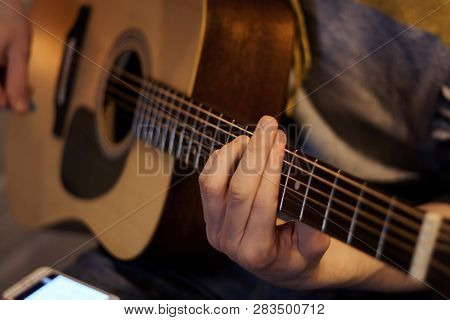 The Singer Plays The Song On An Acoustic Guitar, Holding On His Knee Smartphone, Which Is Written Ly