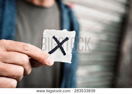 closeup of a young caucasian person holding a piece of paper with a X written in it, for the third gender category