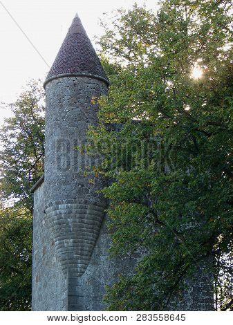 Old Tower With Conus Roof Between Green Branches