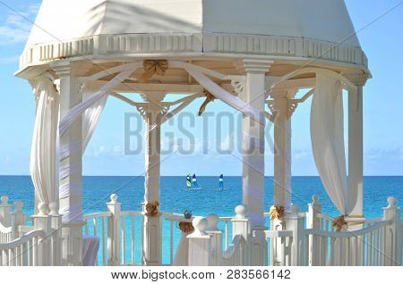 White Wedding Gazebo In A Seaside Tropical Garden At A Destination Wedding Reception. Decorated Chai