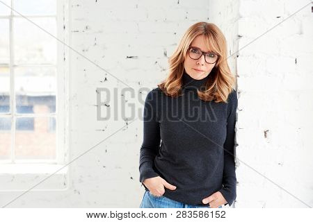 Portrait Of Attractive Woman Wearing Roll Neck Sweater And Jeans While Looking At Camera And Smiling