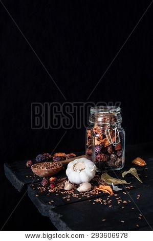 Garlic, Dried Fruit And Seeds In Dark Rustic Background. Artistic Photo Of Garlic And Dry Fruit In A