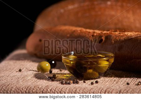 Fresh Bread Baguette With Olive Oil, Olives. Cheese And Rosemary On Wooden Background. Teasty Breakf