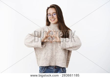Charming Happy And Optimsitic Young Woman In Glasses And Warm Sweater Showing Heart Gesture Expressi