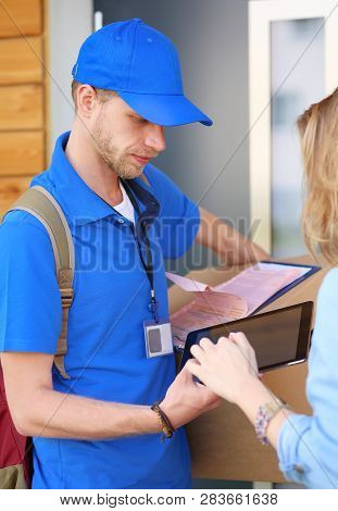 Smiling Delivery Man In Blue Uniform Delivering Parcel Box To Recipient - Courier Service Concept. S
