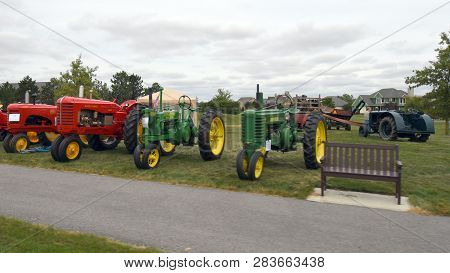 A Row Of Vintage Red And Green Tractors Including John Deere, And Mccormick On Display At The Blufft
