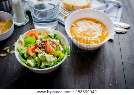 Serving For Lunch, Homemade Pumpkin Soup In White  Bowl And Fresh Light Green Salad Of Vegetables An