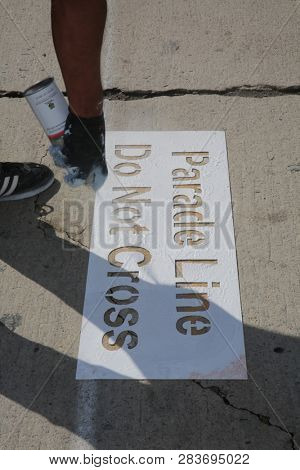 LOS ANGELES - FEBRUARY 9, 2019: Golden Dragon Parade in the streets of China Town Los Angeles. A worker Stencils a Do Not Cross sign on the streets of LA for the Chinese New Year celebration.

