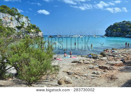 Cala Macarella, Menorca, Spain - August 14, 2018 : People Enjoy The Beach And Turquoise Water In Bay