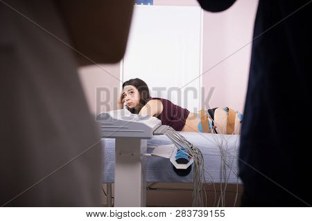 Young Woman With Dark Hair Taking Myostimulation At The Nutritionists Office, Patient Lookinf At The